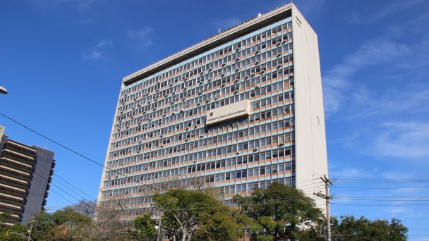 A foto destaca o edifício-sede do Daer, na área central de Porto Alegre. Céu azul com poucas nuvens ao fundo.