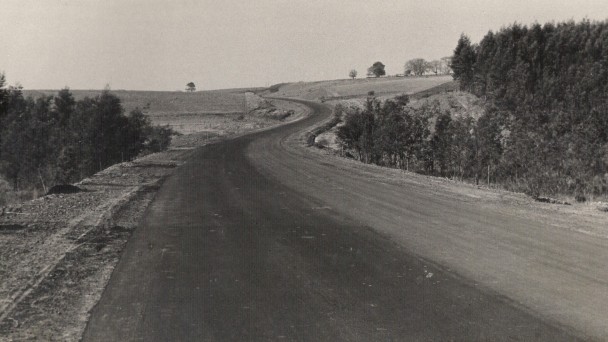 A foto antiga e em preto e branco mostra a Estrada da Produção, atual BR-386, na época de sua pavimentação