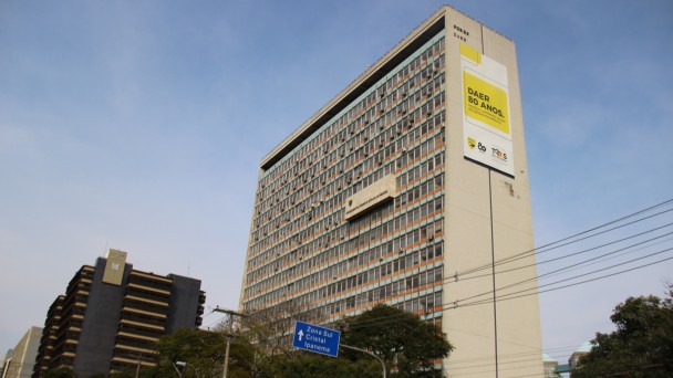 A foto mostra o prédio do Daer, em Porto Alegre, com um banner alusivo aos 80 anos da autarquia, na fachada lateral.