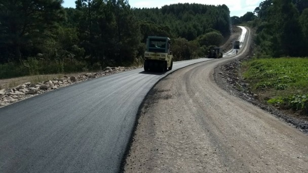 A foto mostra a rodovia ERS-439, que dá acesso ao município de Jaquirana. A pista está íntegra, sem nenhuma imperfeição. Uma máquina da empresa de conserva está realizando o nivelamento do pavimento.