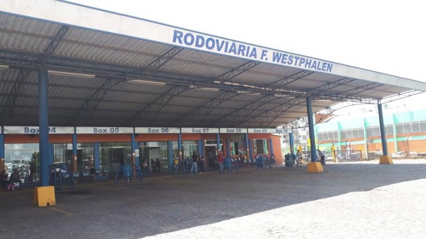 A foto mostra a fachada na rodoviária de Frederico Westphalen. Na estação, algumas pessoas aguardam os ônibus.