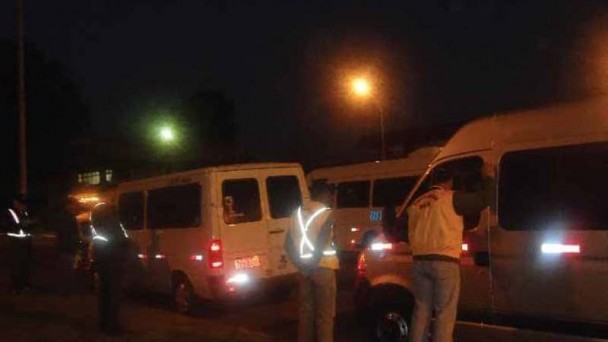 Foto noturna de servidores do Daer, realizando uma fiscalização em vans de fretamento e turismo