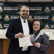 A imagem mostra um servidor do Daer recebendo de um diretor um certificado de homenagem pelos serviços prestados à autarquia.
