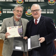 A imagem mostra um servidor do Daer recebendo do secretário dos Transportes um certificado de homenagem pelos serviços prestados à autarquia.