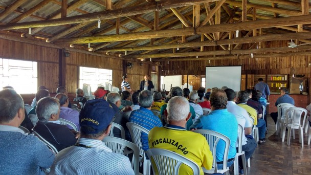 Foto mostra diversos fiscais do Daer sentados em um galpão assistindo uma palestra sobre como realizar as abordagens aos veículos de fretamento e turismo.