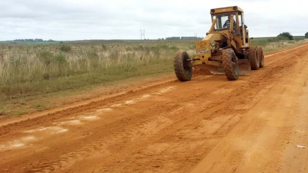 Na foto, uma patrola circula por uma estrada de chão, em obras de manutenção rotineira.