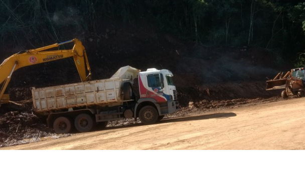 A foto mostra um caminhão e retroescavadeiras fazendo o trabalho de desobstrução da BRS-470