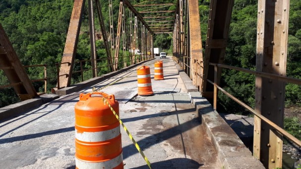 A foto mostra a ponte sobre o rio das Antas. No piso, estão cones indicando a realização de obras na pista.