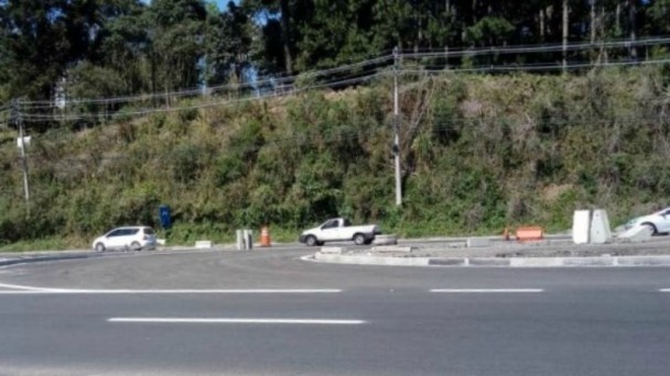 A foto mostra uma rótula e carros transitando. Ao fundo, a vegetação da Serra Gaúcha.