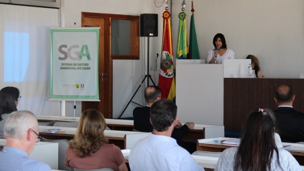 A foto mostra a engenheira Josani discursando para a plateia do evento. Ao fundo, as bandeiras do Rio Grande do Sul e do Brasil