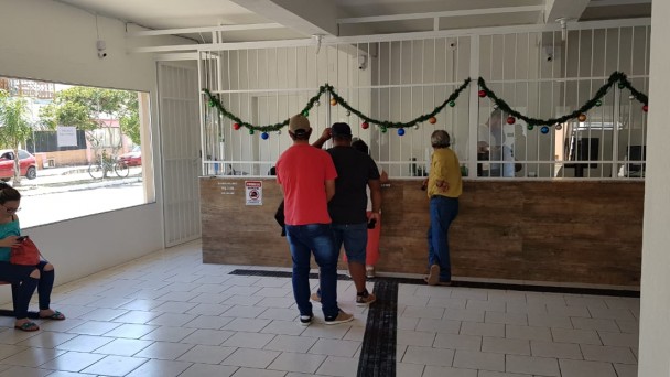 A foto mostra a rodoviária de Arroio Grande. Na fila, estão pessoas aguardando para comprar passagens.