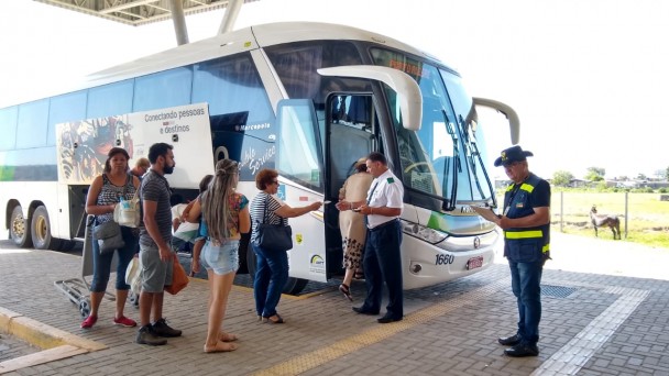 Fiscal do Daer está na rodoviária perto de ônibus, acompanhando o embarque dos passageiros numa ação de fiscalização da autarquia.