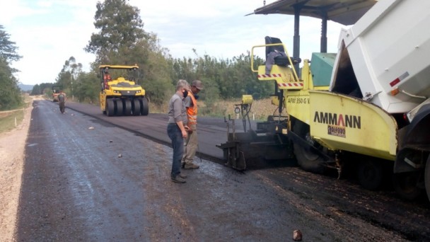 Caminhões e carros de patrolamento em obras e pavimentando uma rodovia 