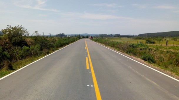 A foto mostra a rodovia ERS-713. No centro, uma pista plana e sinalizada. às margens, vegetação baixa.