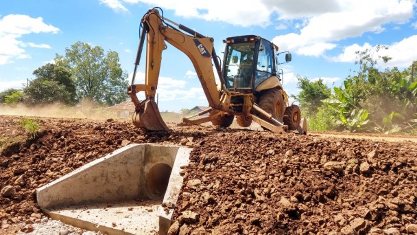 Foto mostra patrola realizando serviço de terraplanagem na rodovia. 