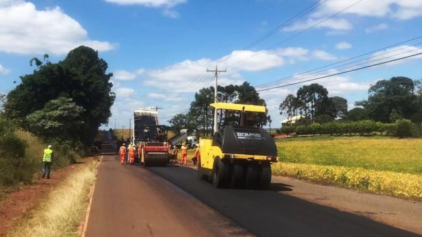 Foto mostra rodovia com maquinas de pavimentação e operários trabalhando.