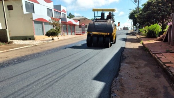 Foto mostra estrada urbana com maquina de pavimentação.
