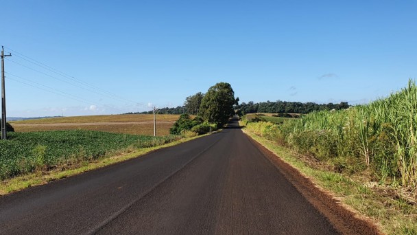 A imagem que representa a matéria é muito bonita. No centro está a estrada pavimentada. Dos dois lados da rodovia está a extensa vegetação, sendo que na parte direita é de milho. Acima da foto está um céu bem azul sem nuvens.