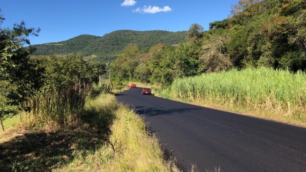 Na foto está a ERS-431 pavimentada com dois carros ao fundo viajando. Dos dois lados da pista está uma grande vegetação, seja de mato, seja de árvores. 