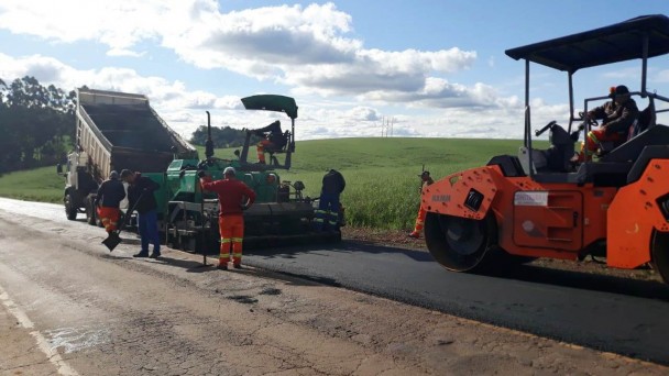 Na foto estão operários trabalhando na recuperação do segmento. Na parte da frente está um caminhão caçamba branco e na na parte de trás uma máquina laranja.