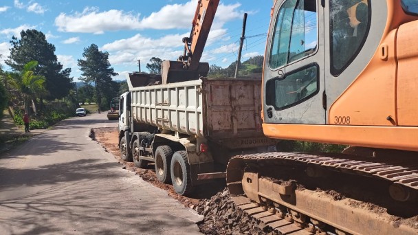 A imagem mostra a máquina recolhendo material do caminhão.