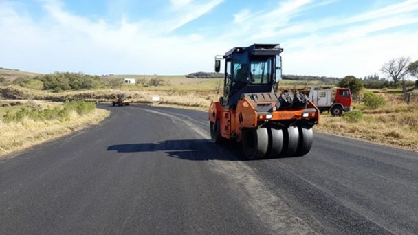 A imagem mostra máquinas trabalhando na compactação do asfalto 