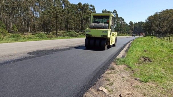 A imagem mostra máquina realizando a compactação do novo asfalto