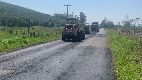 A imagem mostra máquinas realizando a compactação do novo asfalto