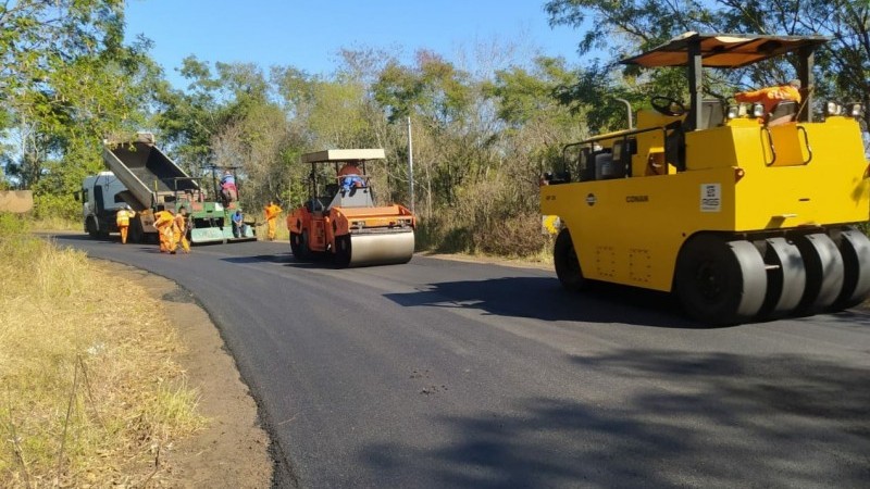 A foto mostra três  máquina circulando sobre o pavimento da rodovia.