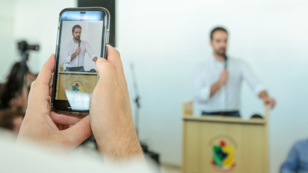 Imagem mostra telefone filmando o discurso do governador Eduardo Leite