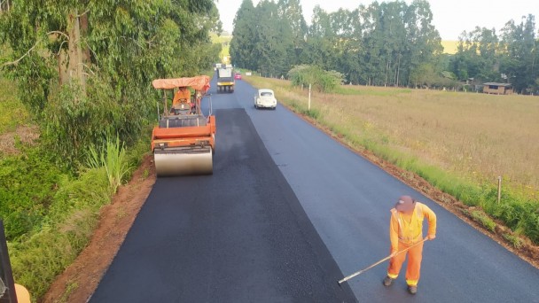 Imagem mostra homem e máquina realizando a compactação do asfalto