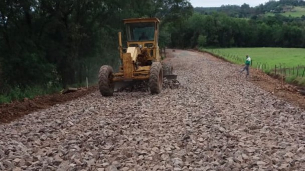 Imagem mostra máquinas colocando a base asfáltica