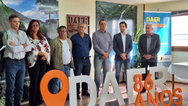 A imagem mostra os diretores do Daer. Em frente deles, há um letreiro escrito "Daer 86 anos"