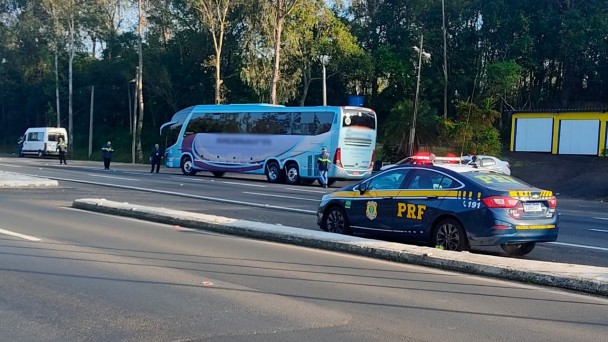 A foto mostrar um automóvel da PRF. Ao fundo, um ônibus sendo vistoriado pelos fiscais.