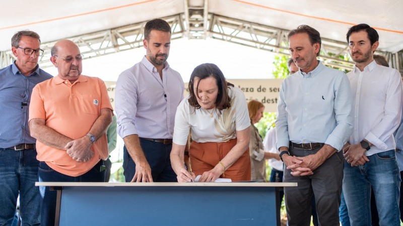 Foto da prefeita de Alegria, Terezinha Zavascki, assinando o documento de ordem de início do acesso asfáltico da ERS-520, observada pelo governador Eduardo Leite e demais autoridades.