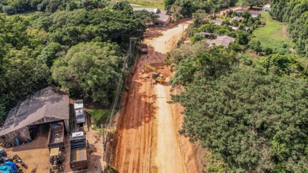 Máquina executa terraplanagem em pista com árvores na lateral
