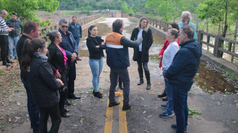 Imagem mostra secretário Costella reunido com homens e mulheres sobre a ponte que será reconstruída entre São Valentim do Sul e Santa Tereza, na Serra gaúcha