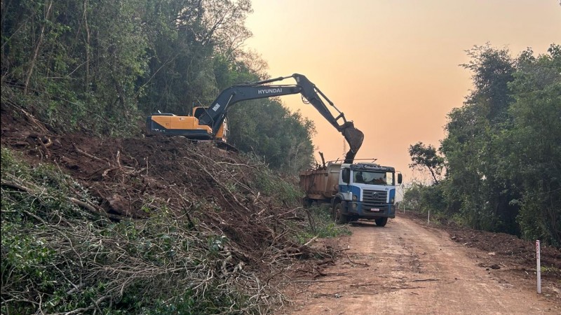 A foto mostra uma retroescavadeira e um caminhão trabalhando nas obras de pavimentação da ERS-305.