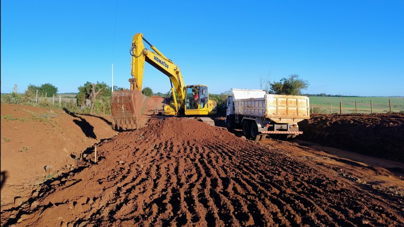 A foto mostra um caminhão e uma retroescavadeira nas obras do acesso a Garruchos, no noroeste do RS